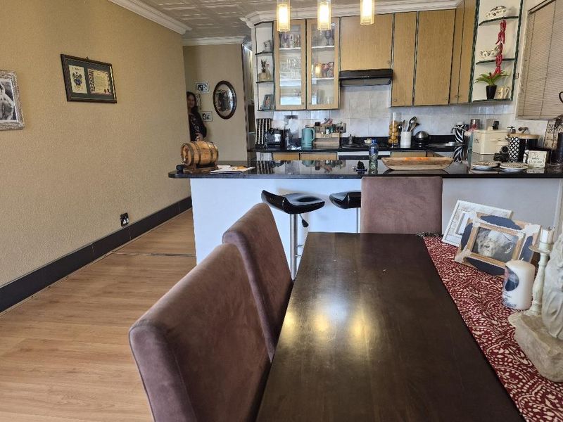 Open-plan living and dining area featuring a kitchen with granite countertops, breakfast bar, and laminate flooring throughout.