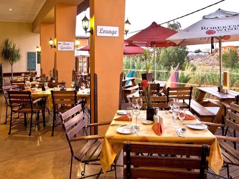 A spacious covered outdoor patio area featuring polished concrete floors, structural pillars, and integrated lighting, suitable for dining and social gatherings.