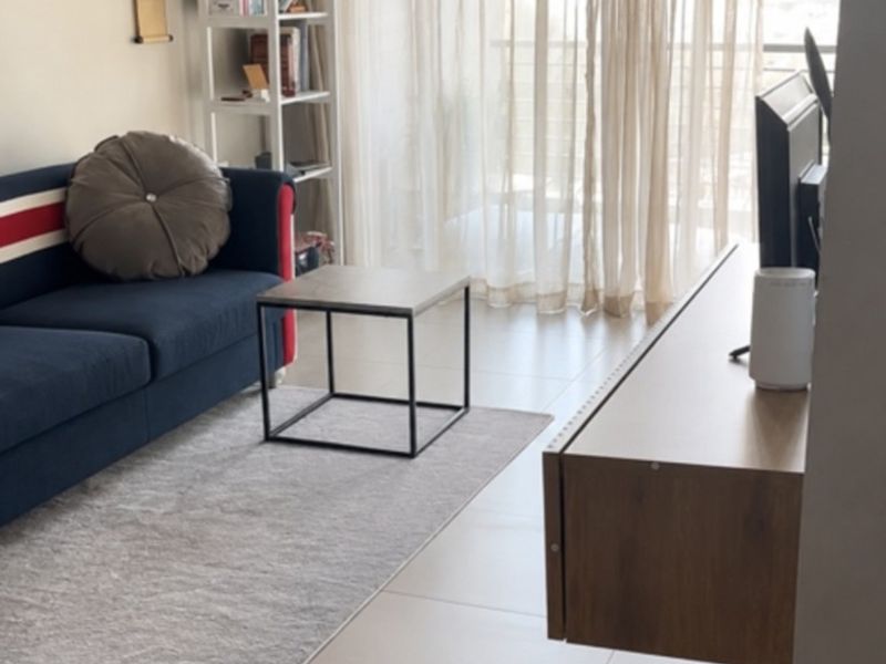 A bright living room featuring neutral tiled flooring, a modern floating media console, and large sliding glass doors leading to an outdoor area.