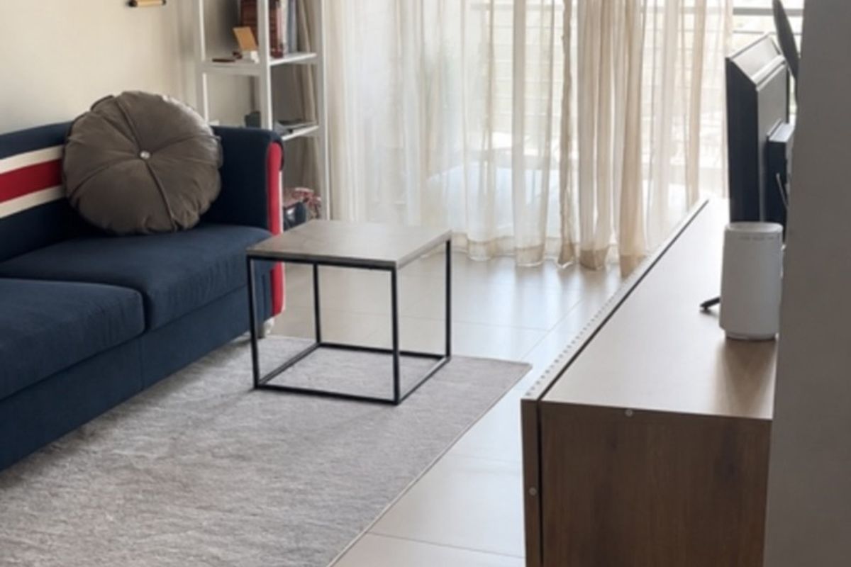 A bright living room featuring neutral tiled flooring, a modern floating media console, and large sliding glass doors leading to an outdoor area.