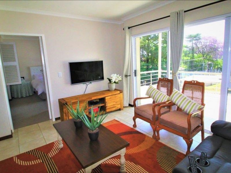 A bright living room featuring tiled flooring and a large sliding glass door that provides access to an outdoor balcony area.