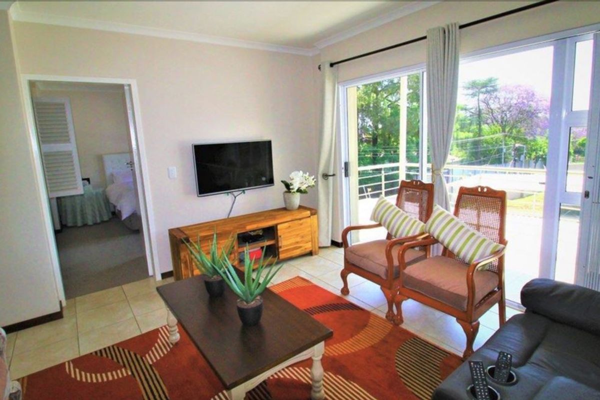 A bright living room featuring tiled flooring and a large sliding glass door that provides access to an outdoor balcony area.