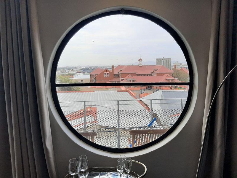 A unique circular window framing an urban cityscape view, providing natural light and a distinct architectural feature to the interior space.