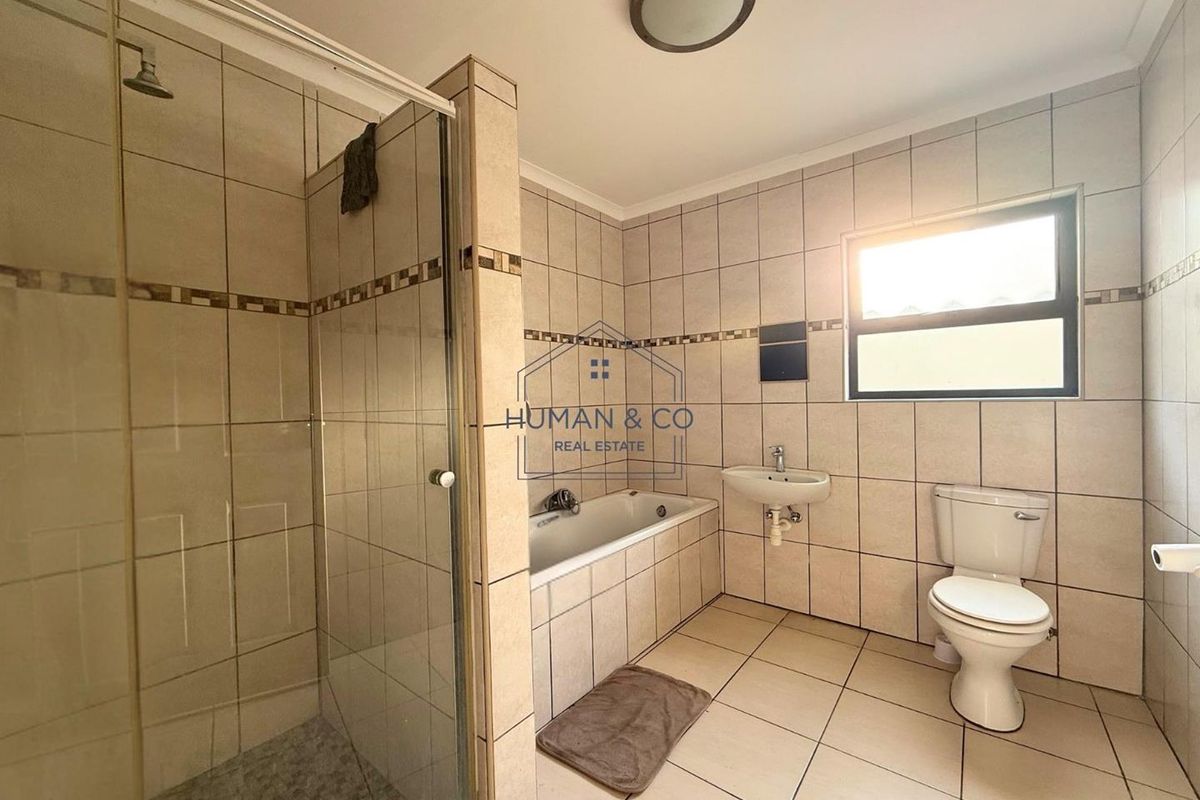 A functional bathroom featuring a separate shower enclosure, a built-in bathtub, a wall-mounted basin, and a standard toilet with tiled walls and flooring.