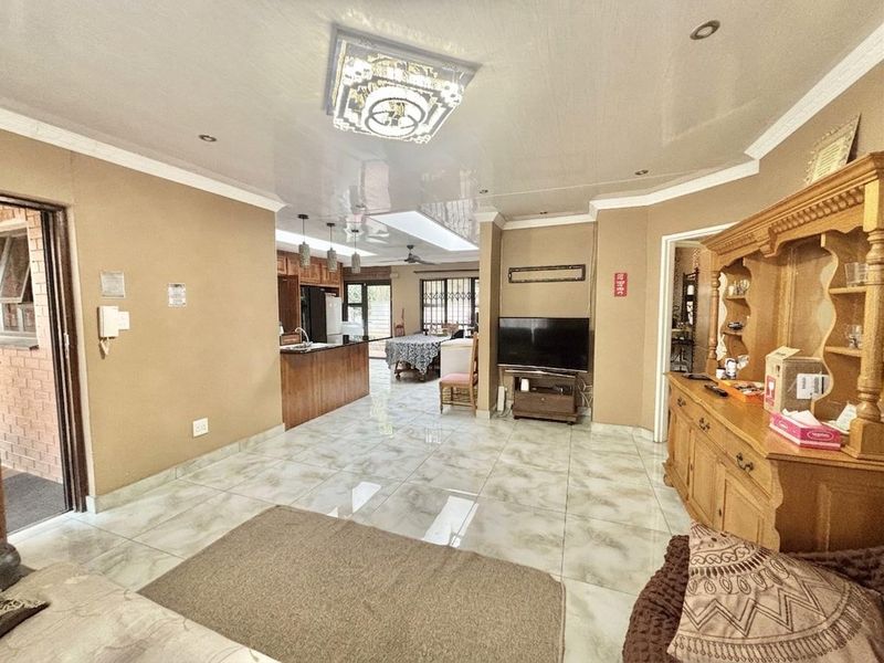 Open-plan living and kitchen area featuring tiled flooring, recessed lighting, and a central kitchen island, creating a functional and connected living space.