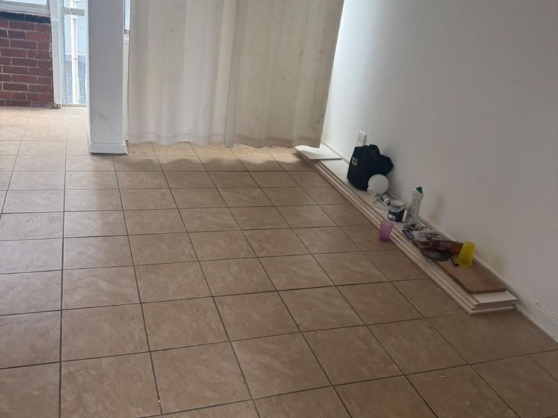 An empty living area featuring tiled flooring and access to an outdoor space through a sliding glass door.