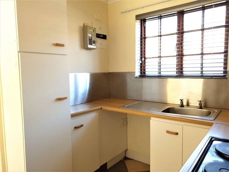A functional kitchen featuring built-in cabinetry, a stainless steel sink with splashback, laminate countertops, and a built-in hob.