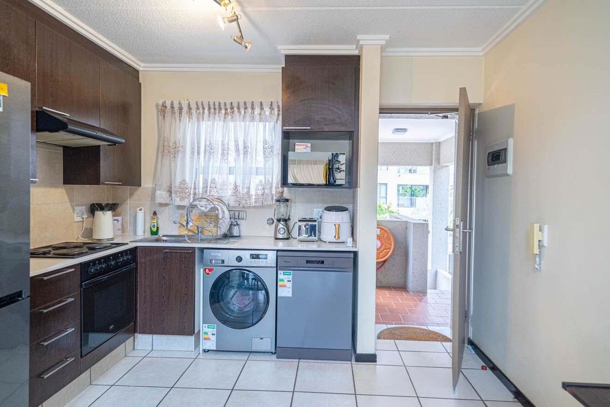 A functional kitchen featuring dark wood cabinetry, tiled flooring, built-in oven and hob, and direct access to an outdoor area.