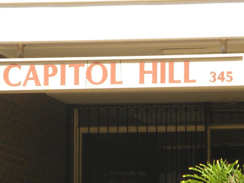 Exterior view of the Capitol Hill apartment building entrance featuring prominent signage and a secure gated entry.