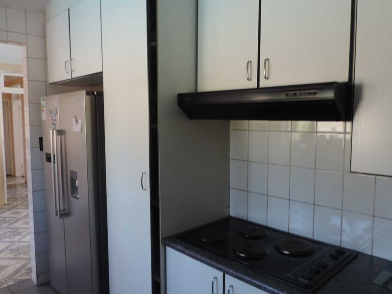 A functional kitchen featuring white cabinetry, a tiled backsplash, and a built-in electric hob with an overhead extractor fan.