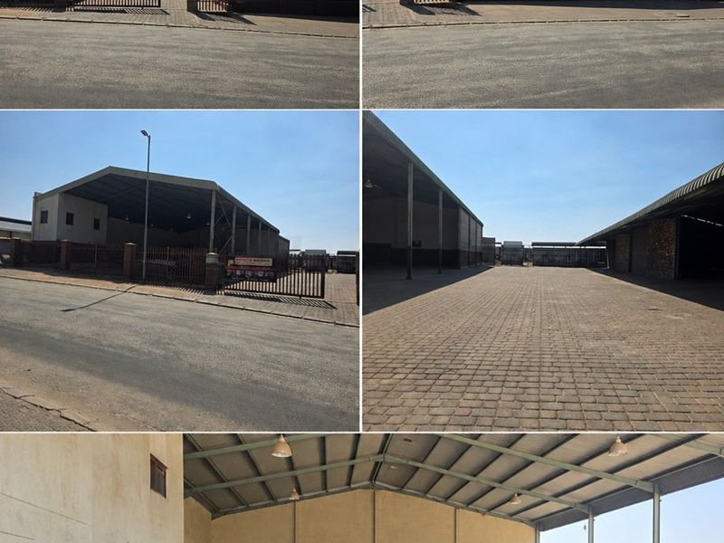 Industrial property featuring a large paved yard, secure gated entrance, and expansive open-plan warehouse structure with steel framing and high ceilings.