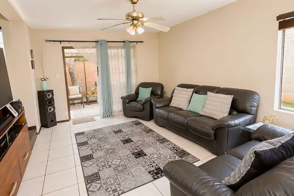 A bright living room featuring tiled flooring, a ceiling fan, and sliding glass doors that provide direct access to an outdoor patio area.