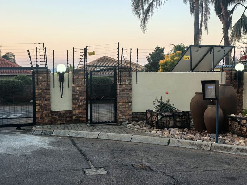 Secure front entrance featuring a brick boundary wall, electric fencing, sliding gate, pedestrian access, and an intercom system with solar-powered lighting.