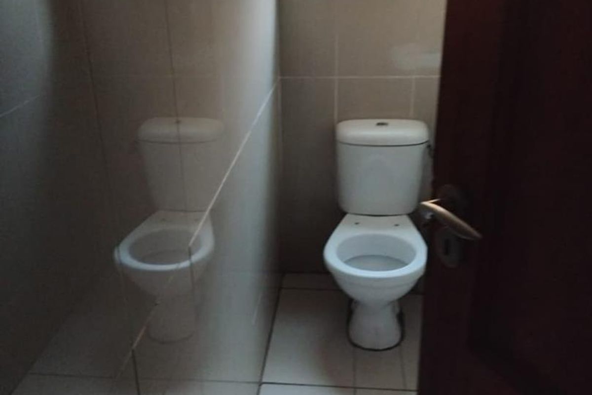 A clean, functional guest bathroom featuring tiled walls, tiled flooring, and a private toilet with a frosted glass window for natural light.