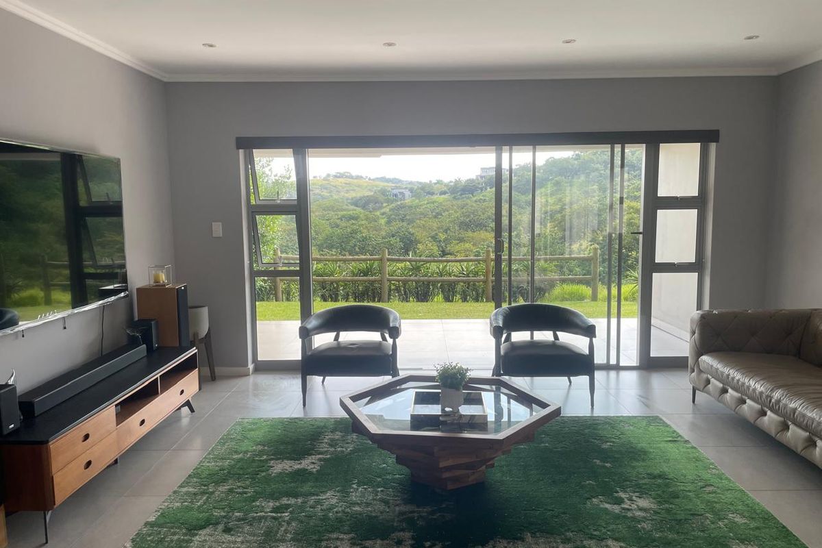 Spacious living room featuring large sliding glass doors that open to a scenic outdoor view, complemented by modern tiled flooring and recessed ceiling lighting.