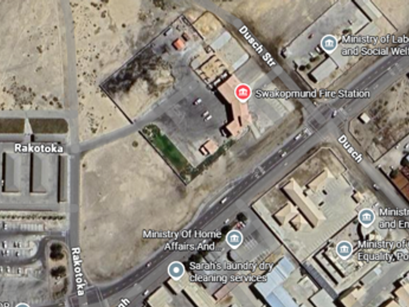 An aerial satellite view showing the industrial area layout, including various government buildings, parking facilities, and surrounding road infrastructure.