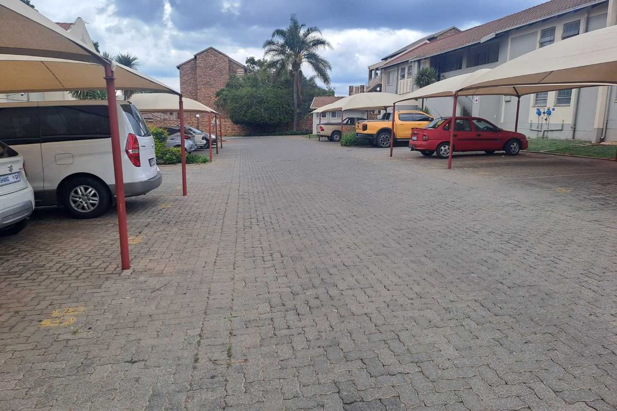 Outdoor parking area featuring paved ground surfaces and multiple covered shade-cloth parking bays for residents.