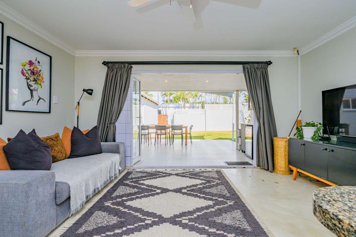 A bright living room featuring large sliding glass doors that open onto a covered patio and rear garden area.