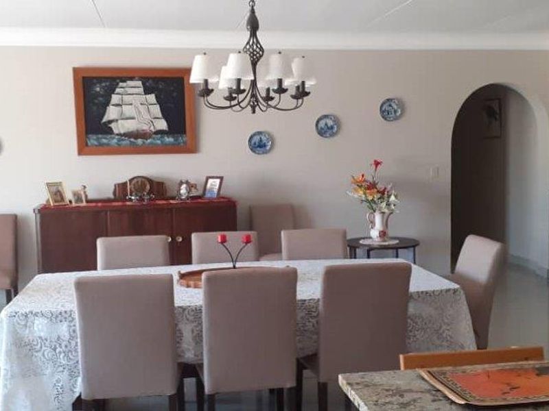 Spacious dining room featuring tiled flooring, decorative archways, and a classic chandelier, providing an elegant space for formal meals and gatherings.