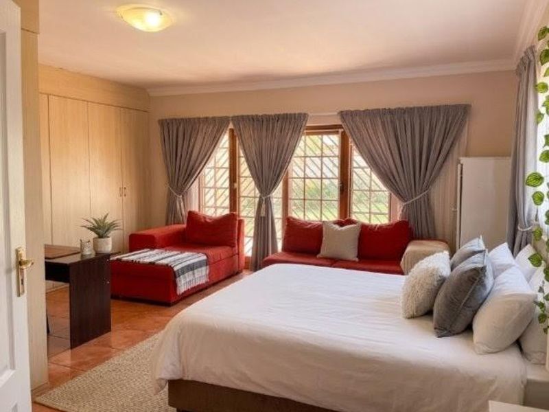 Spacious bedroom featuring built-in cupboards, tiled flooring, and large windows with curtains, offering a comfortable and functional living space.