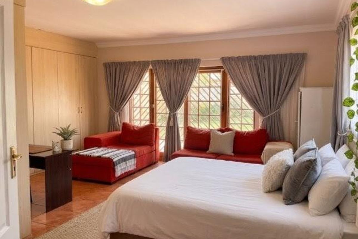 Spacious bedroom featuring built-in cupboards, tiled flooring, and large windows with curtains, offering a comfortable and functional living space.