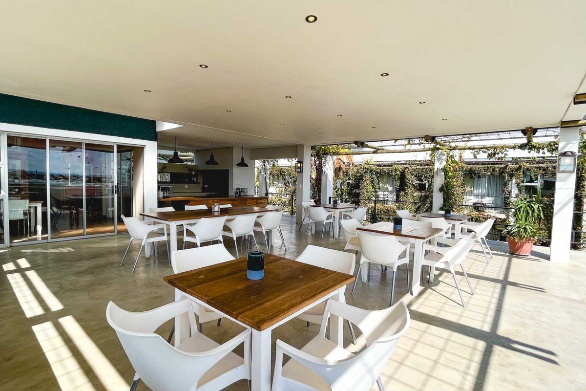 A spacious covered outdoor patio featuring concrete flooring, recessed lighting, and direct access to the interior through large sliding glass doors.