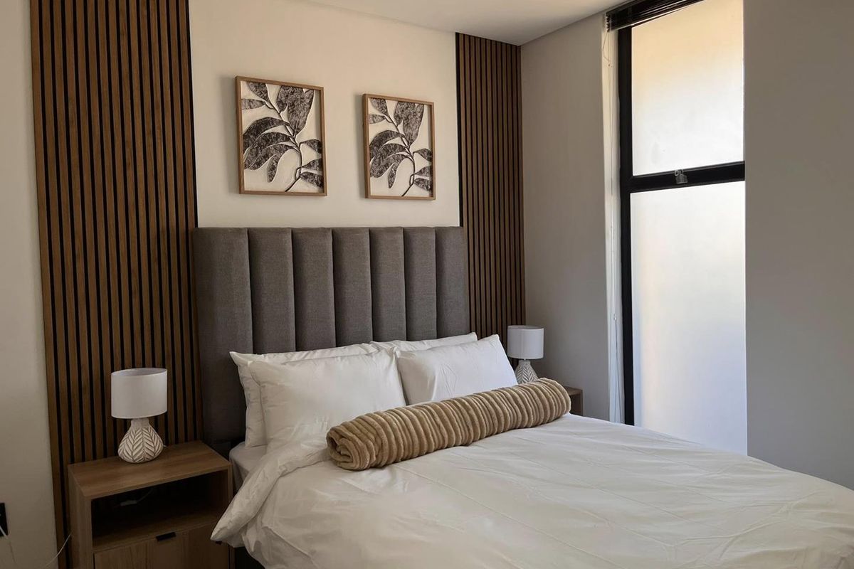 A modern bedroom featuring stylish timber slat wall paneling and a large window that allows for ample natural light.