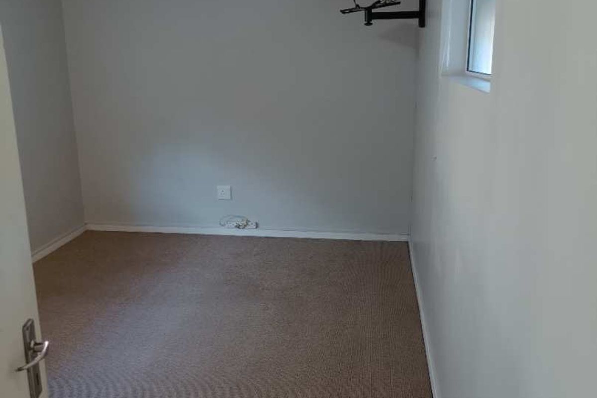 A vacant bedroom featuring carpet flooring and a timber tongue and groove ceiling, offering a blank canvas for potential updates.