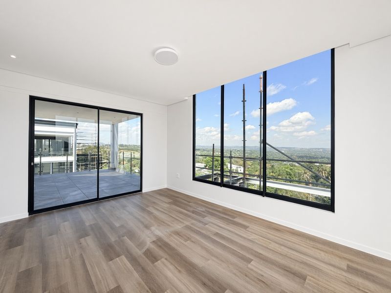 A bright, modern, and empty living area featuring floor-to-ceiling windows, sliding doors to a balcony, and high-quality laminate wood flooring.