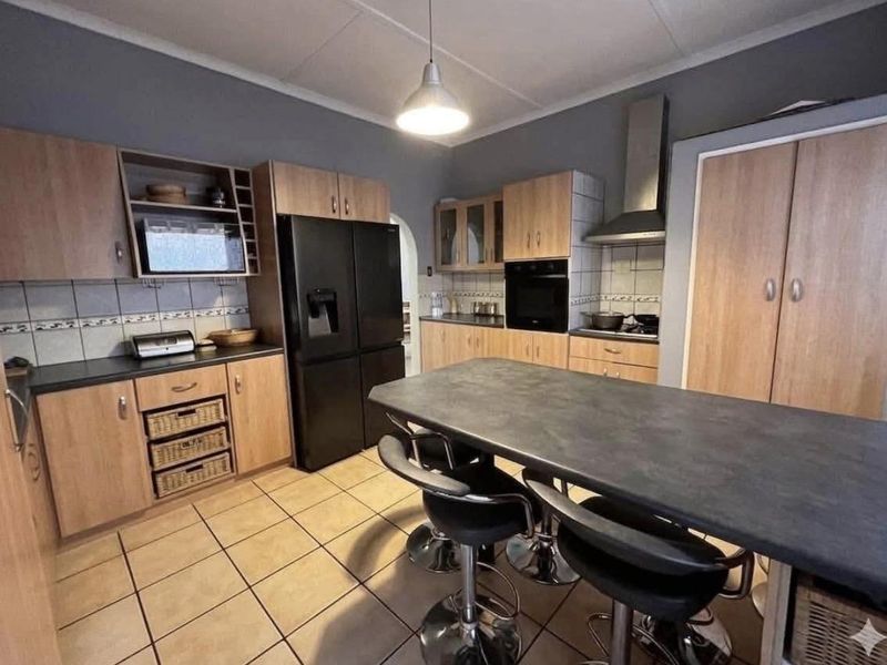 A functional kitchen featuring wood-finish cabinetry, dark countertops, a central island, and tiled flooring, providing a practical workspace for daily cooking and dining.