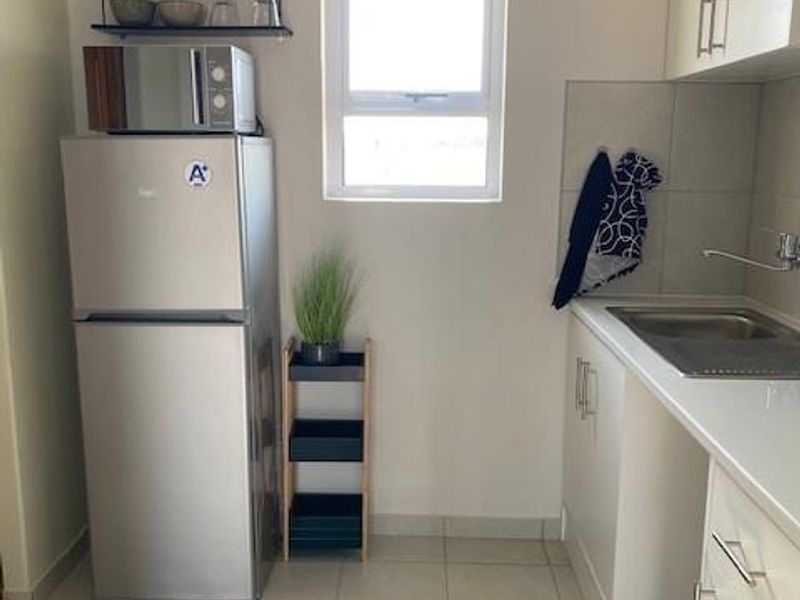 A functional kitchen area featuring tiled flooring, built-in cabinetry, a stainless steel sink, and a window providing natural light.