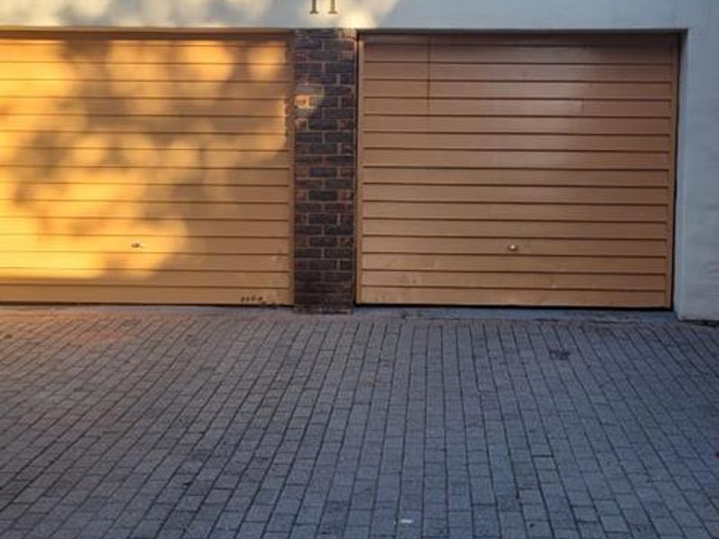 A double garage with horizontal panel doors and a paved driveway entrance.