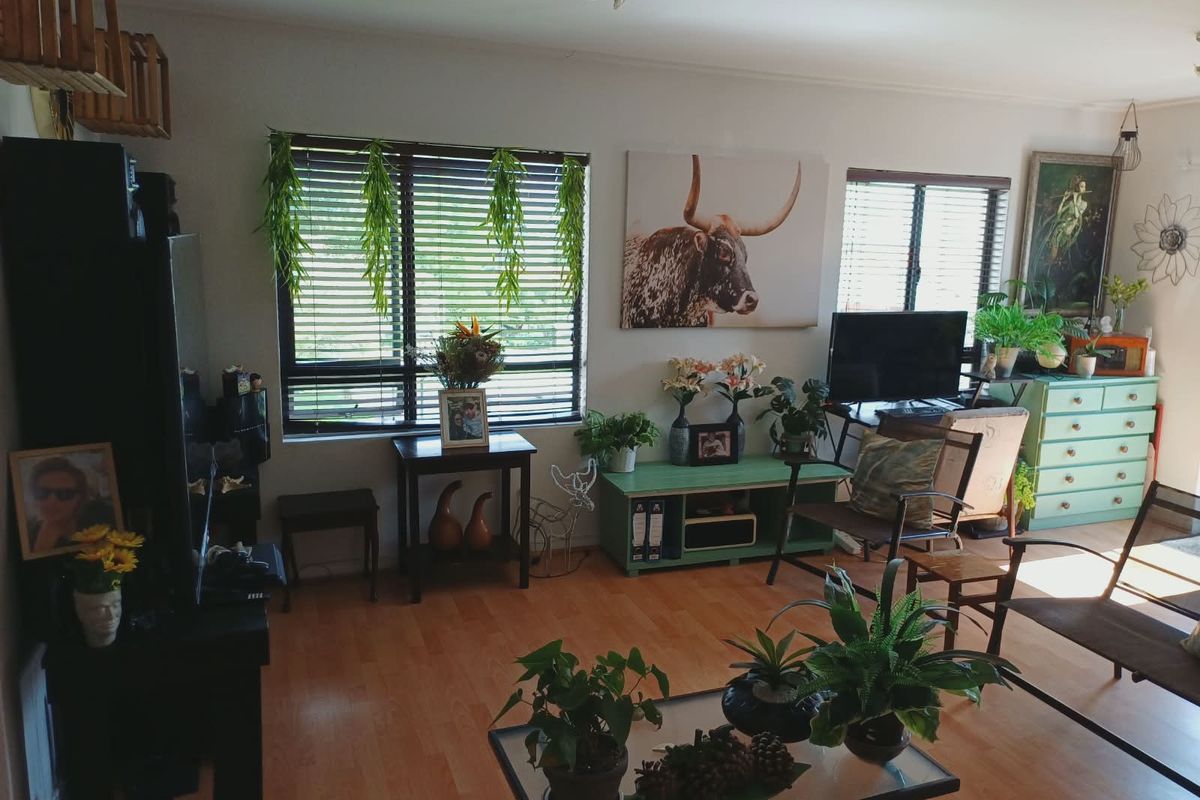 A living room featuring laminate flooring and venetian blinds, offering a functional space with natural light.