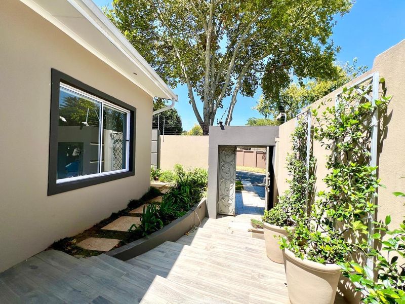 A well-maintained front entrance area featuring tiled flooring, a secure gate, and perimeter walling with integrated electric fencing.