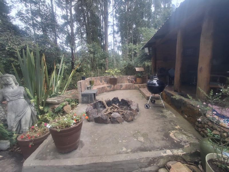 Outdoor patio area featuring a stone fire pit, built-in stone bench seating, and a covered section with timber support posts.