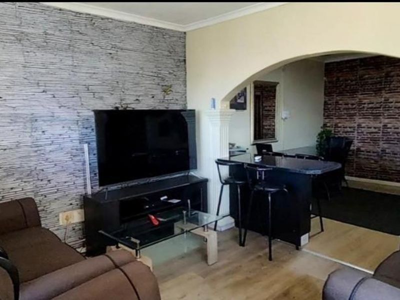 Open plan living area featuring a textured accent wall, arched transition, and decorative columns connecting to the adjacent dining space.