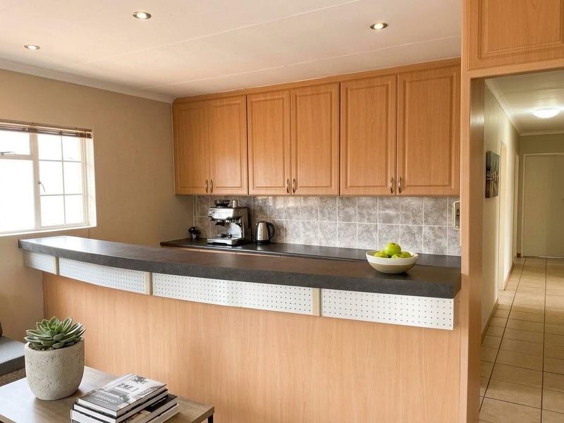 A functional kitchen area featuring light wood-tone cabinetry, a tiled backsplash, and a breakfast bar counter, providing a practical workspace.