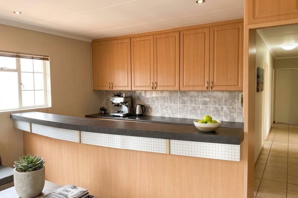 A functional kitchen area featuring light wood-tone cabinetry, a tiled backsplash, and a breakfast bar counter, providing a practical workspace.