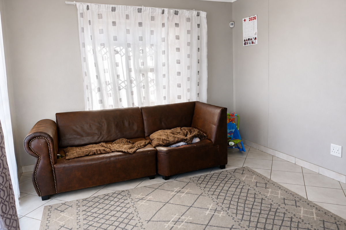A living room featuring neutral wall paint, ceramic tiled flooring, and a window fitted with a curtain rod.