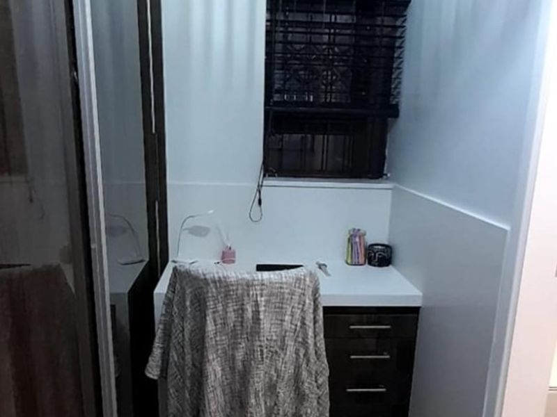 A compact home office featuring a built-in desk with integrated cabinetry, tiled flooring, and a sliding door wardrobe.