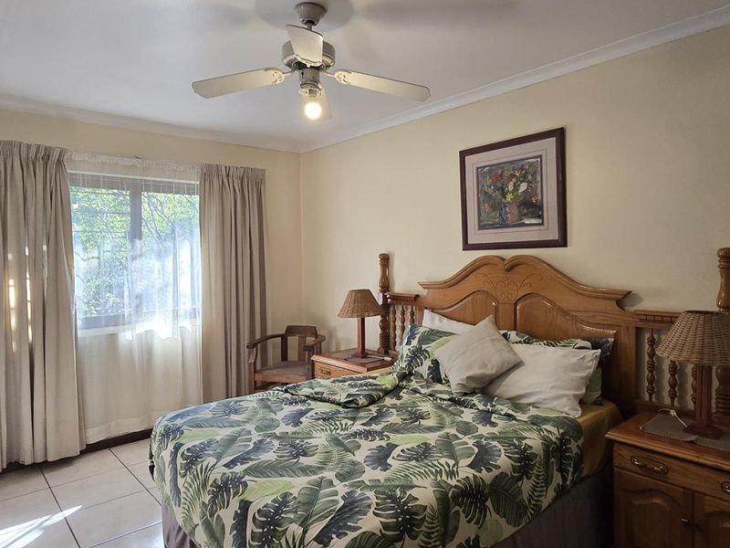 A functional bedroom featuring tiled flooring, a ceiling fan, and a built-in wardrobe, offering a comfortable and practical living space.