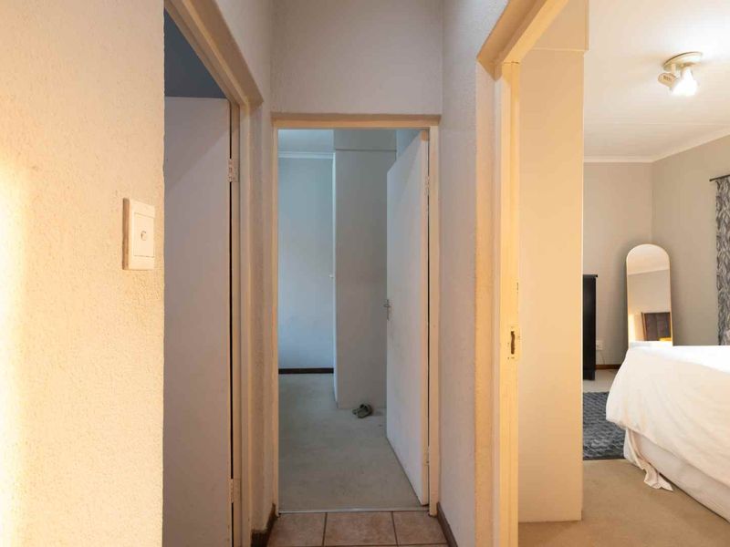 A functional hallway connecting multiple rooms, featuring a mix of tiled and carpeted flooring with standard internal door frames.
