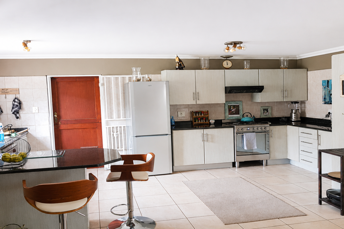 A functional kitchen featuring granite countertops, ample cabinetry, a breakfast bar, and a freestanding oven, with tiled flooring throughout.