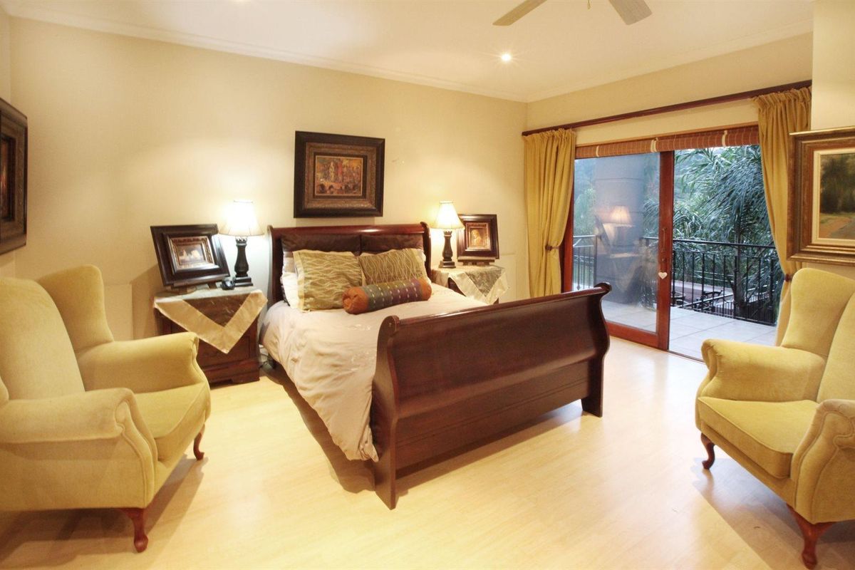 Spacious bedroom featuring light wood-look flooring, a ceiling fan, and large sliding glass doors that open onto a private balcony.