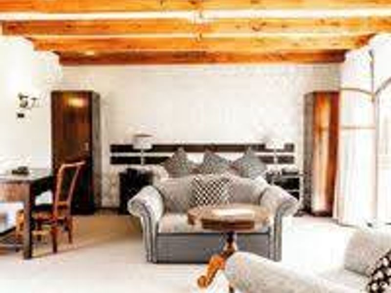A bedroom featuring exposed timber ceiling beams, built-in wardrobes, and a custom headboard, offering a rustic aesthetic with functional storage solutions.