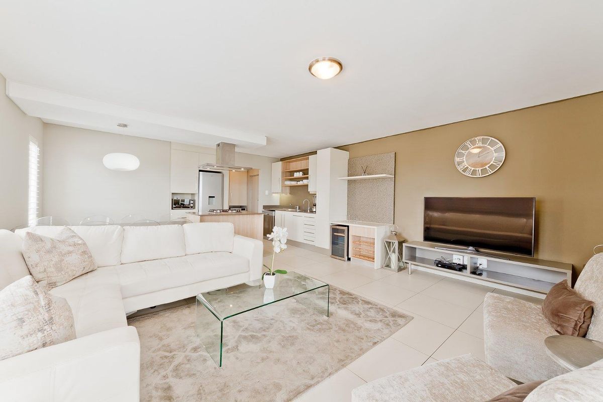 Open-plan living area featuring a modern kitchen with built-in cabinetry, stainless steel extractor fan, and tiled flooring throughout.