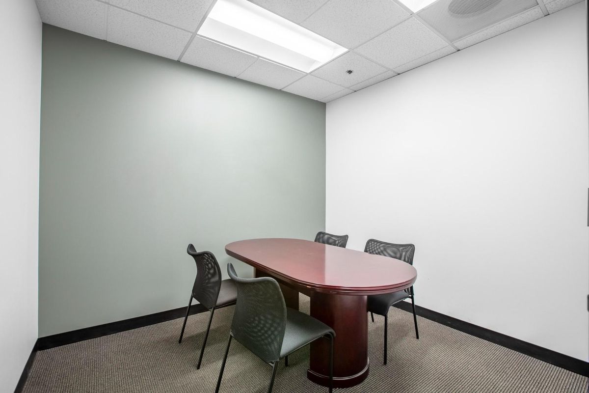 A professional office meeting room featuring a suspended ceiling, recessed lighting, and carpeted flooring.