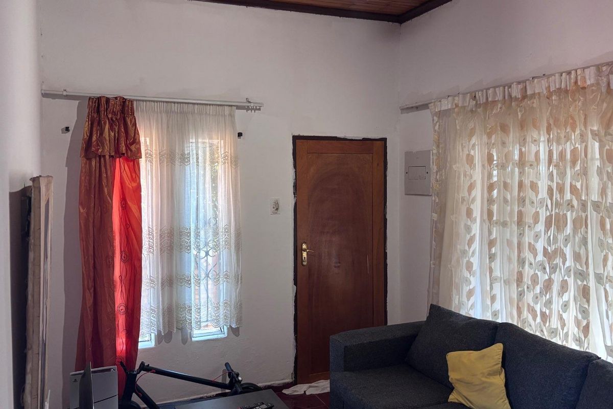 A living room area featuring a timber ceiling, wooden door, and electrical distribution board, requiring cosmetic updates to improve the overall finish.