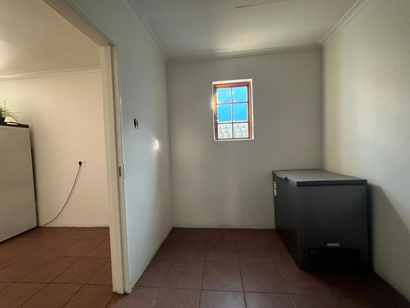 A functional utility space featuring tiled flooring and a small window, providing a practical area for storage or additional office equipment.