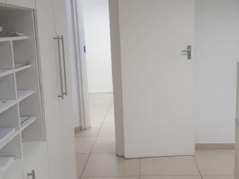 A functional office space featuring built-in white cabinetry, tiled flooring, and a clean, neutral aesthetic suitable for a professional work environment.